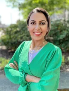 Dr. Elahi stands outside in front of green trees.