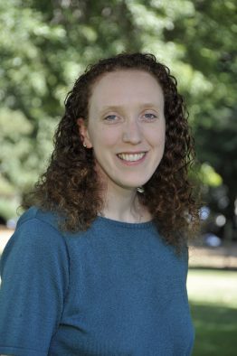 Miriam Weiser standing outside in front of green trees.