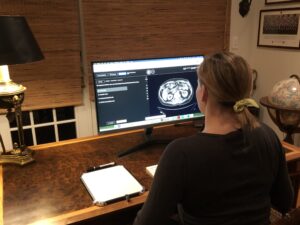 A woman sitting at a desk views a sample exam question on a computer screen.