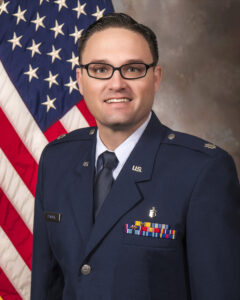 Dr. Peacock in uniform in front of the American flag.